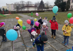 Dzieci w ogrodzie przedszkolnym w oczekiwaniu na wypuszczenie balonów „do nieba”.